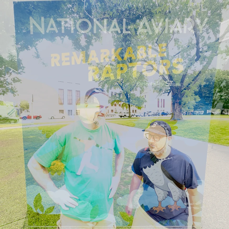 Two people outdoors layered with trees and a National Aviary sign.