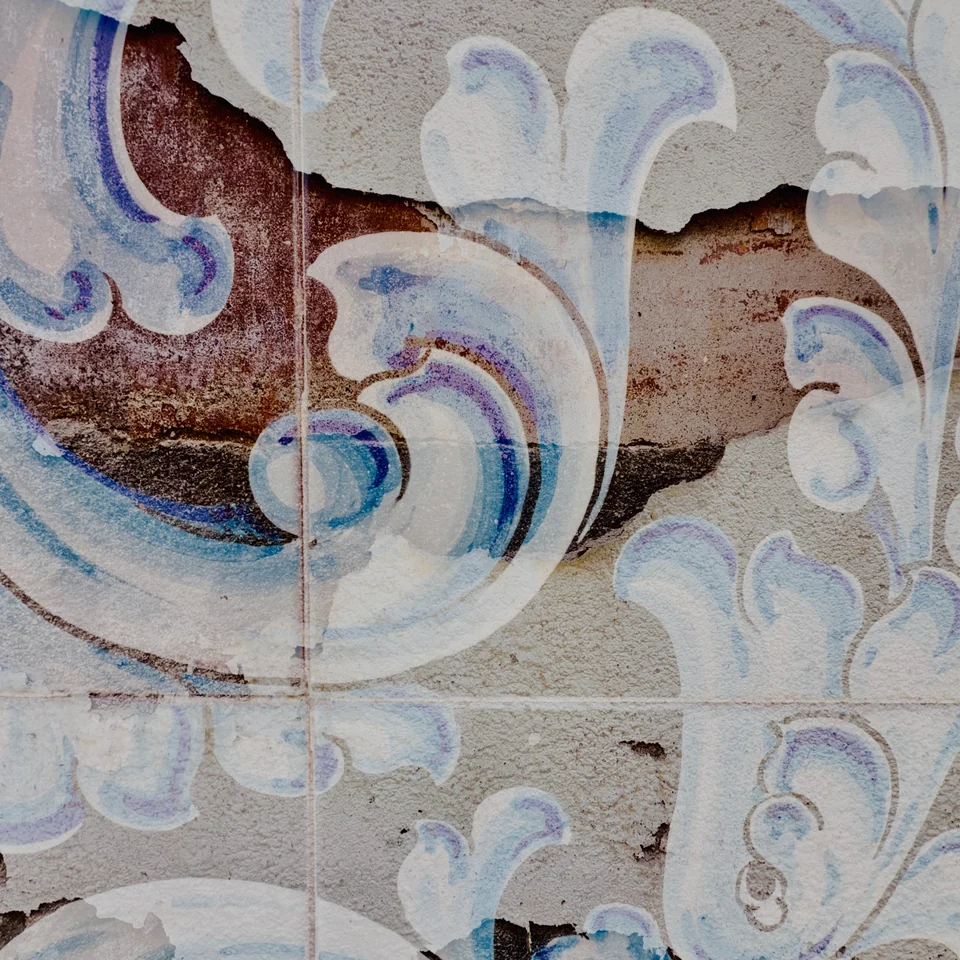Blue and white ceramic scrollwork layered over weathered stone.