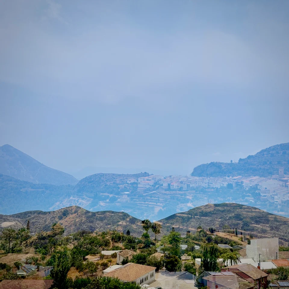 Hazy blue mountains layered above a coastal town.